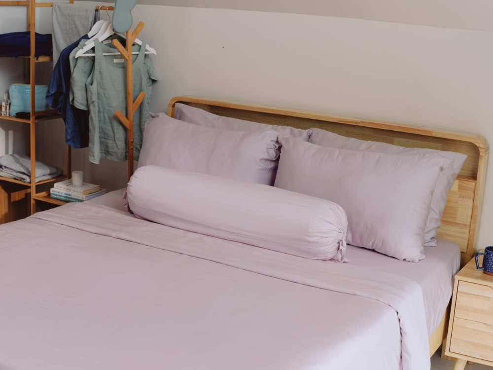light purple pillowcases, bolster and bedsheets on a bed