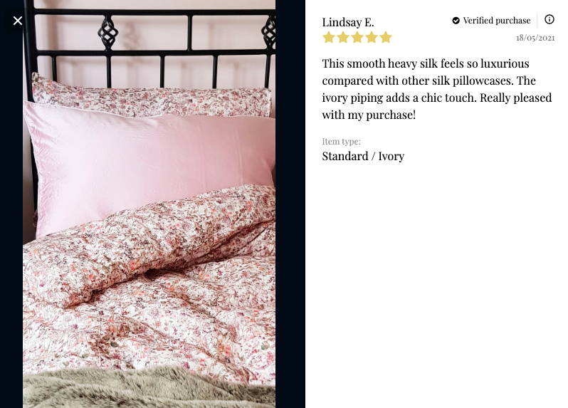 Funda de almohada rosa sobre una cama con una cita de reseña que dice: