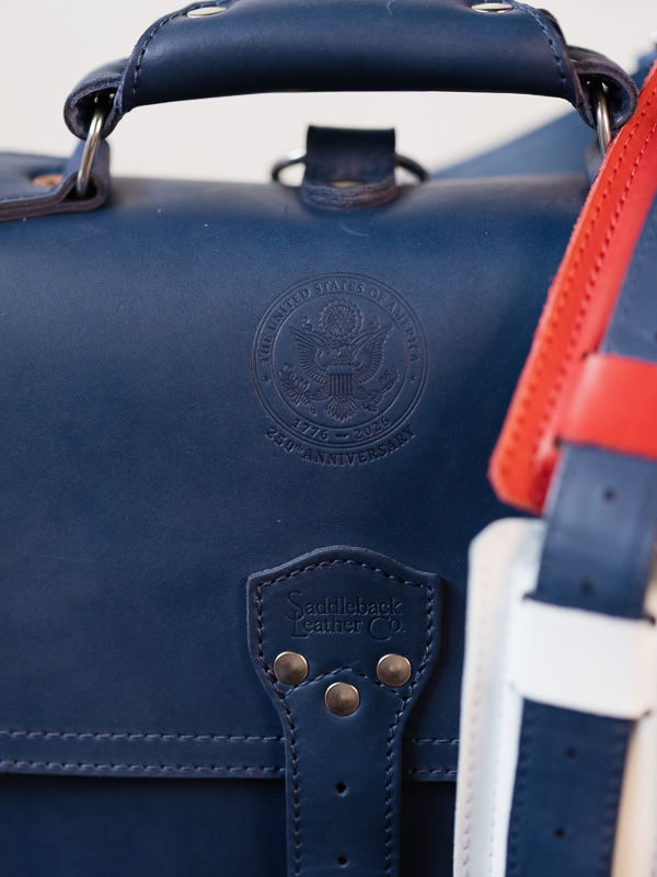 Close-up of a blue leather bag with colorful straps.