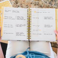open planner with writing on it, gold binding, on women's lap