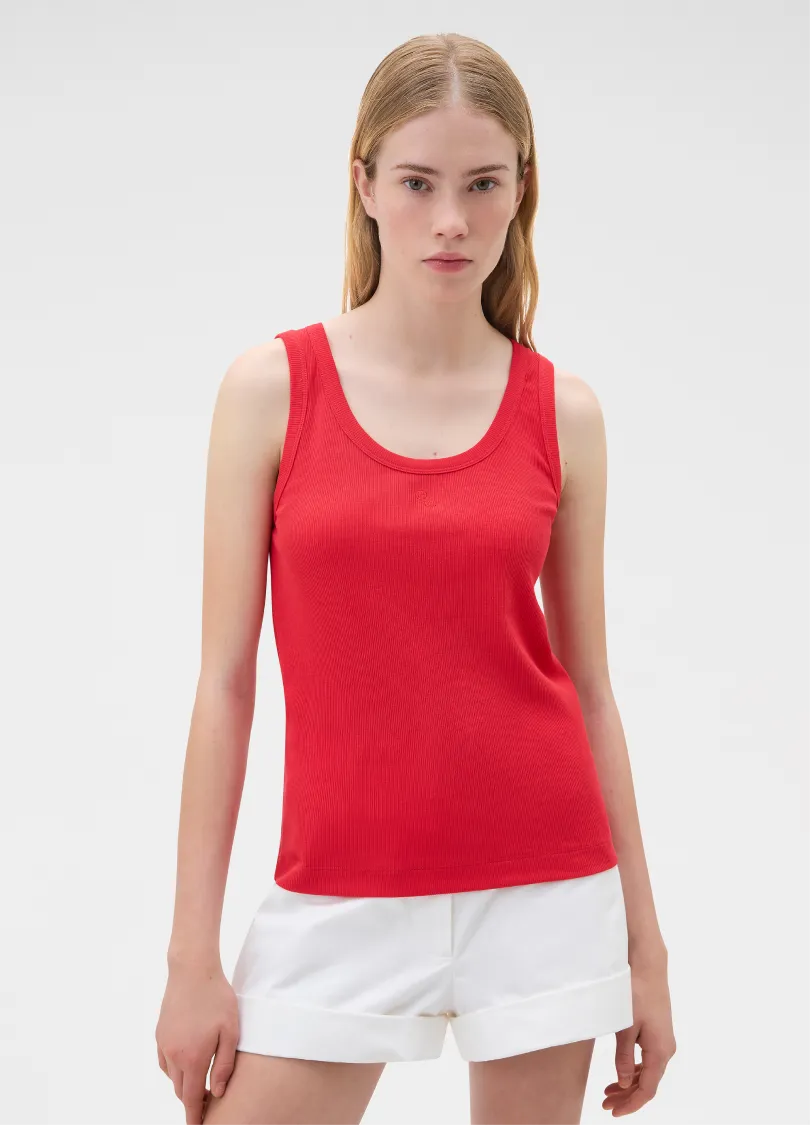 Model wearing a red tank top and white shorts against a plain background.