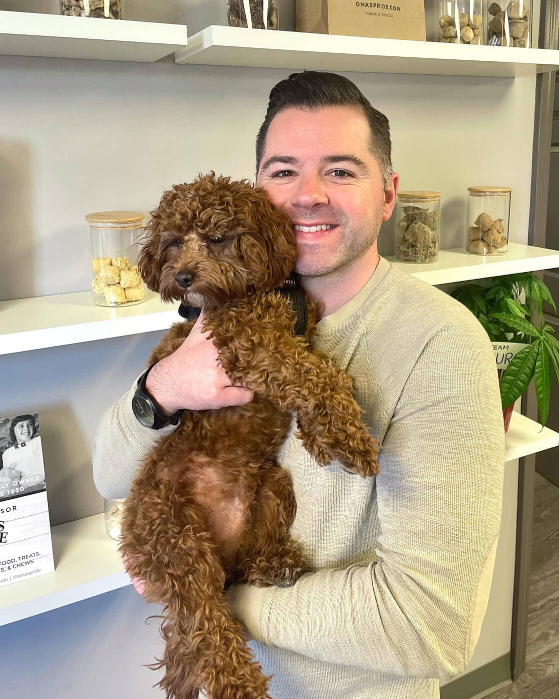 Adam holding his dog Lincoln next to white shelves.