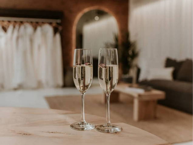 Dos copas de champán llenas en el primer plano de una sala de exposiciones de novias 