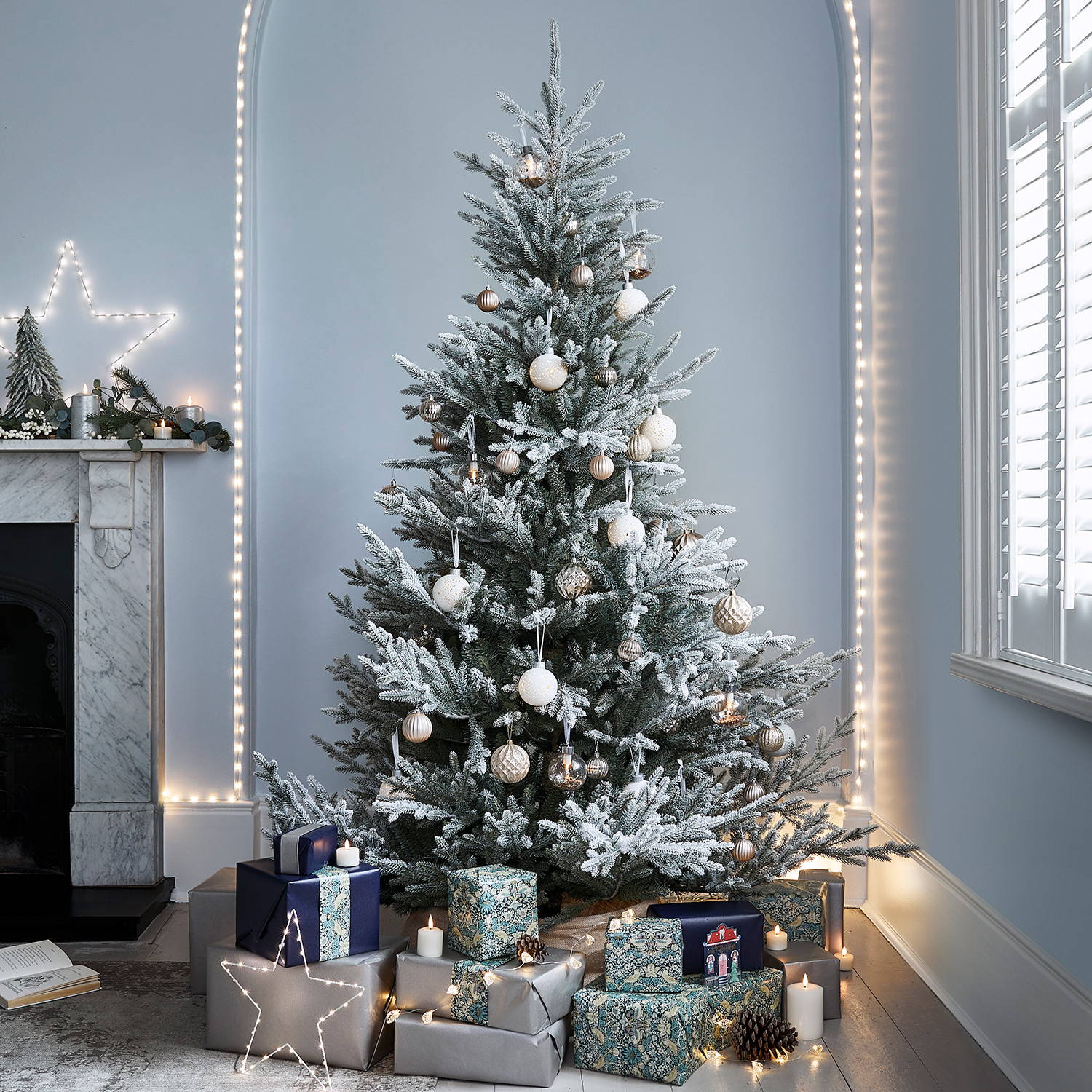 Flocked tree with white and cool toned baubles in a living room.