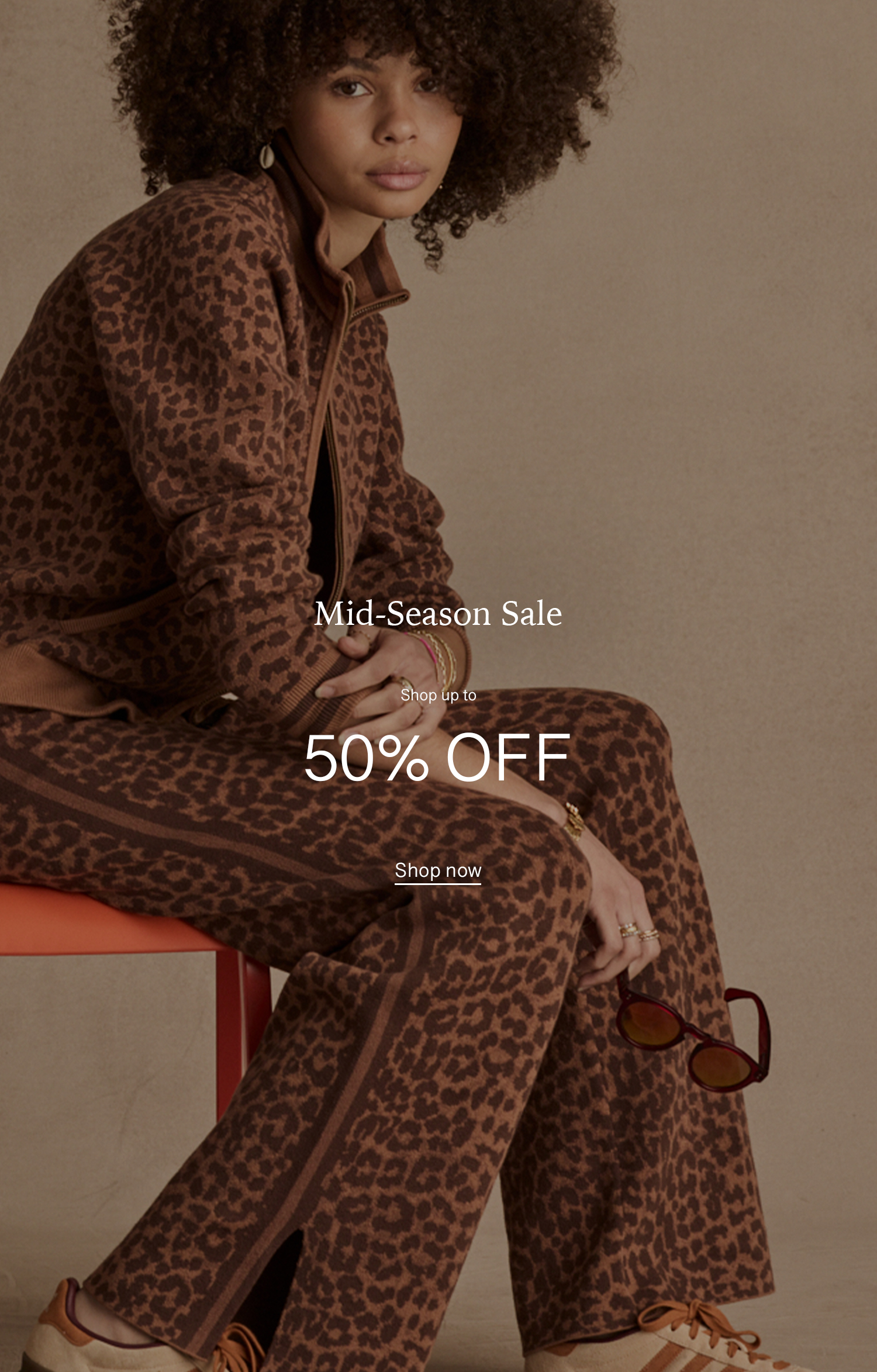 Model in leopard print outfit promoting mid-season sale, 50% off.