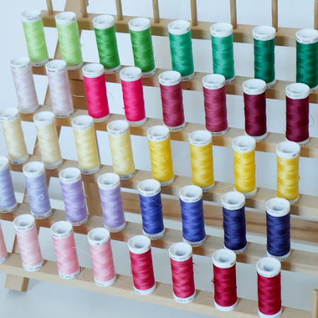 Spools of cotton thread in different colors on a thread rack