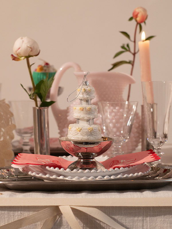 A decorative table setting with a small cake and flowers.