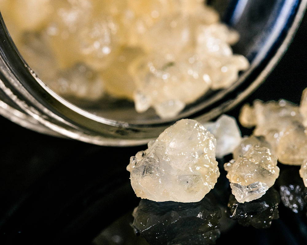 A photo close up of cannabis diamonds outside a container.