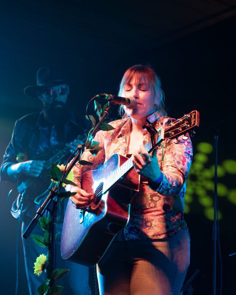 Musicians performing on stage, one playing guitar and singing.