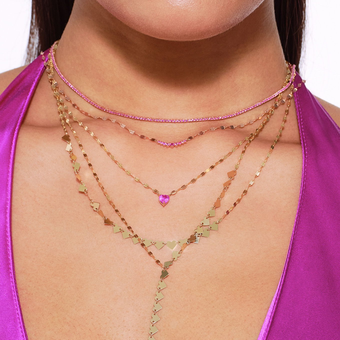 Close-up of layered necklaces worn with a purple top.
