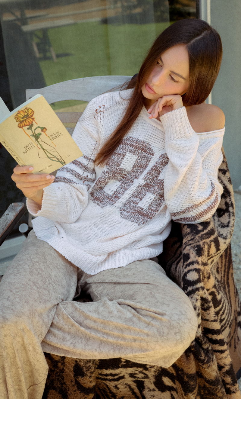 Person reading a book while sitting on a chair, wearing casual clothing.