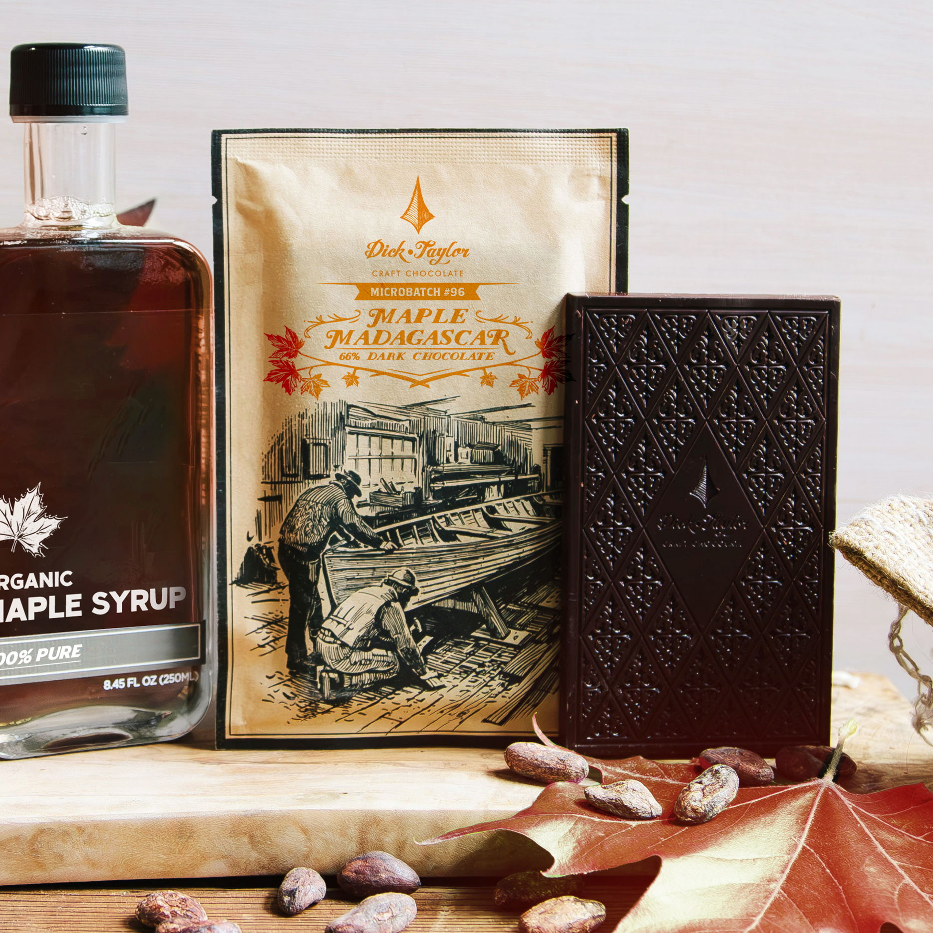 Maple Madagascar Microbatch with bottle of maple syrup, cocoa beans and red maple leaves