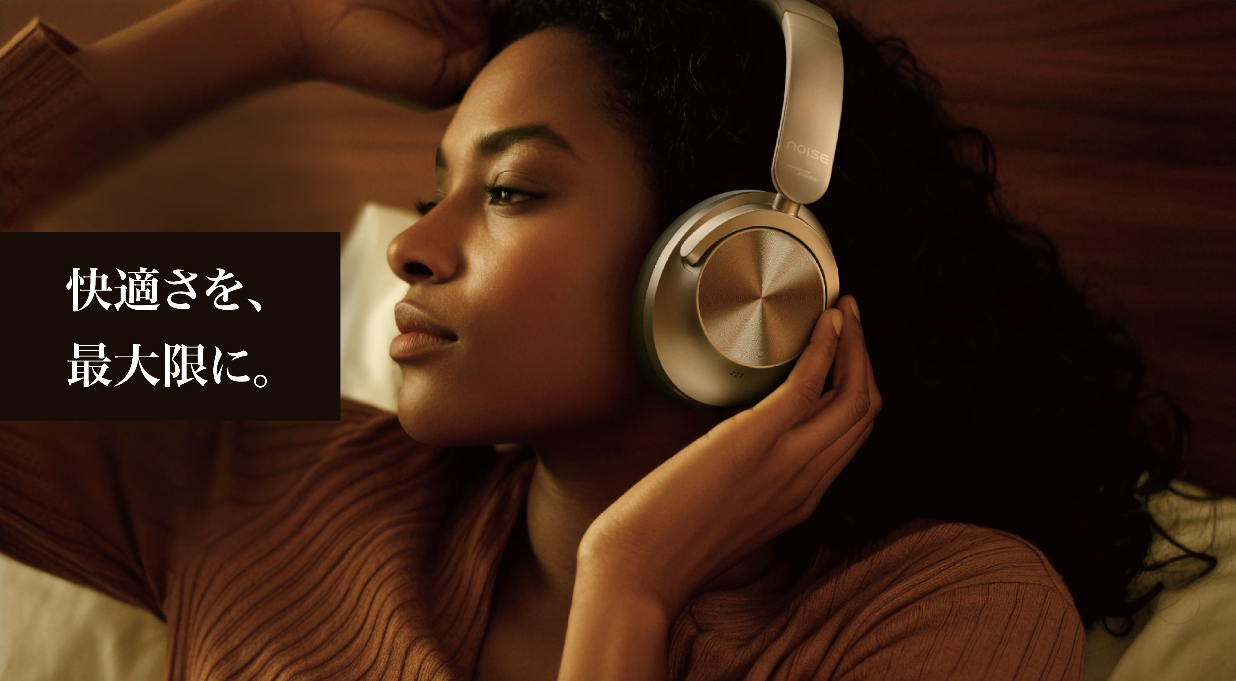 Woman wearing headphones, enjoying music in a cozy setting.