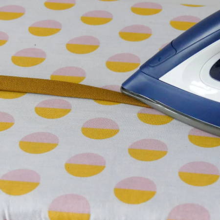 Ironing fusible hem tape onto a fabric strip to make the handles of a tote bag