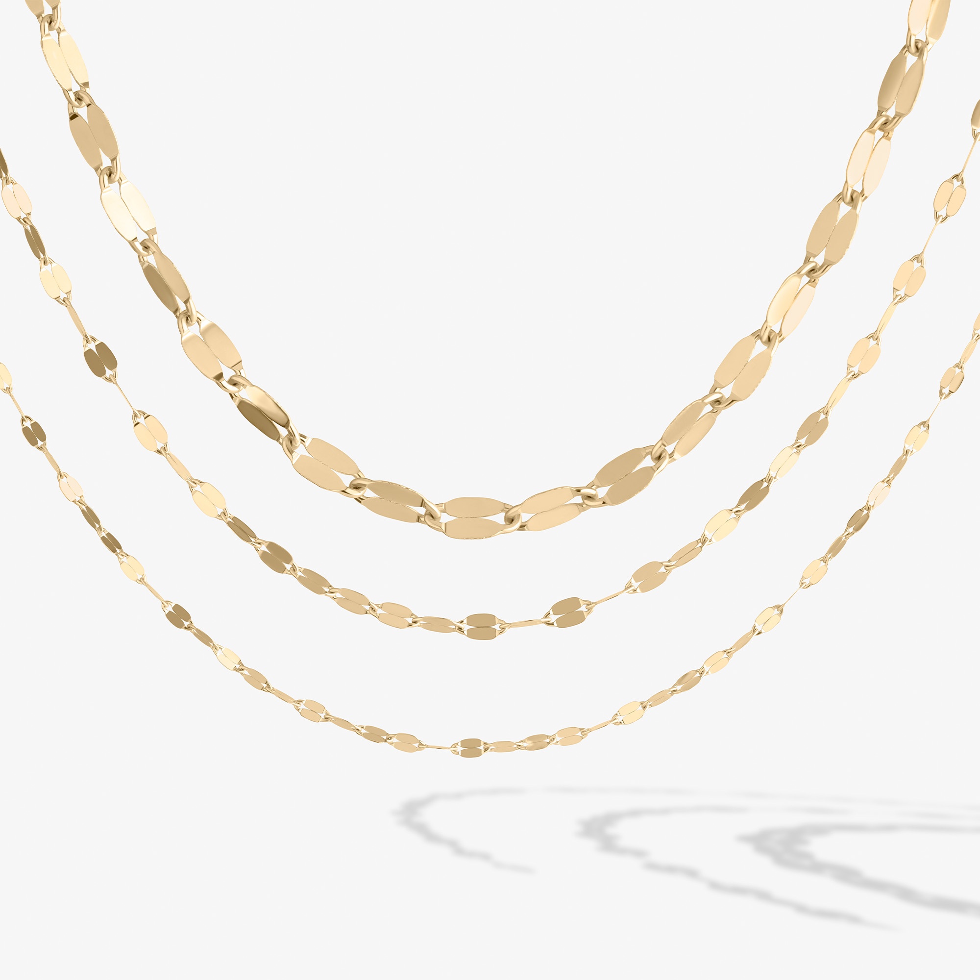 Three layers of gold chain necklaces on a white background.