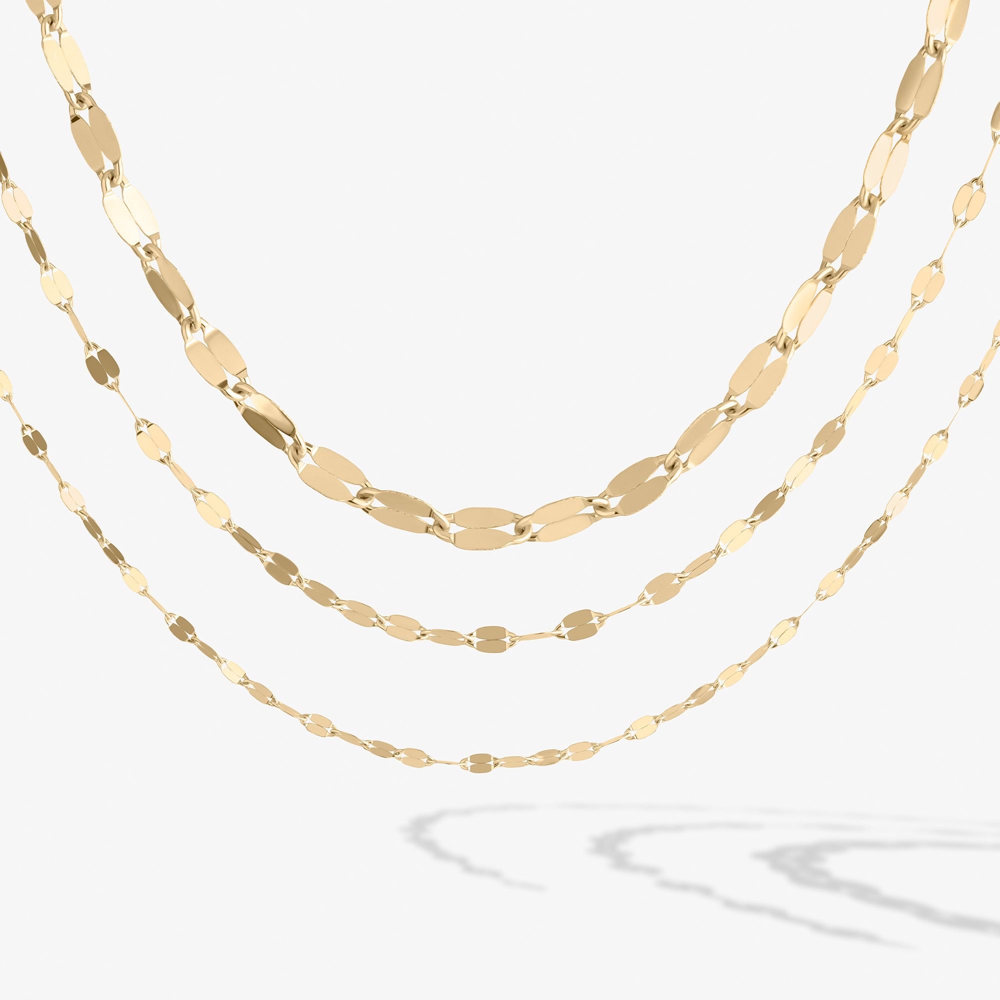 Three layers of gold chain necklaces on a white background.