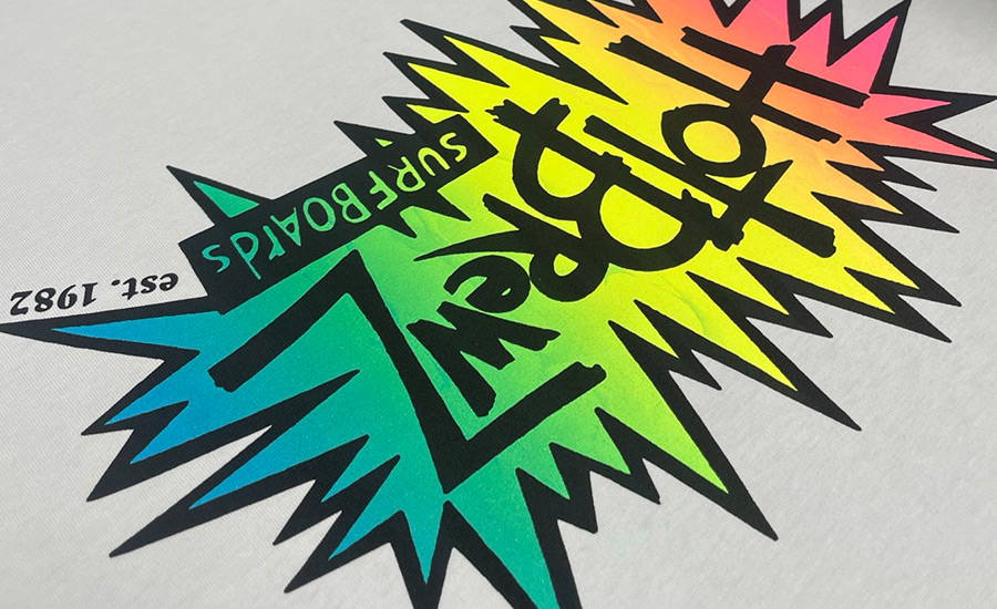 A screenprinted rainbow neon blend of specialty inks of the 'Hot Brewz Surfboards' logo on a white tshirt. The star callout shape is a blend of neon red, orange, fluro yellow, fluro green, and blue and the logotype and border is spot colour printed in black on top.