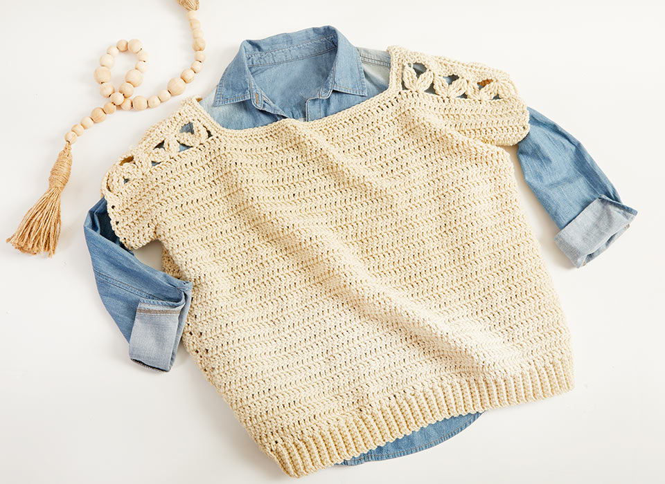 Beige knitted sweater over a denim shirt.