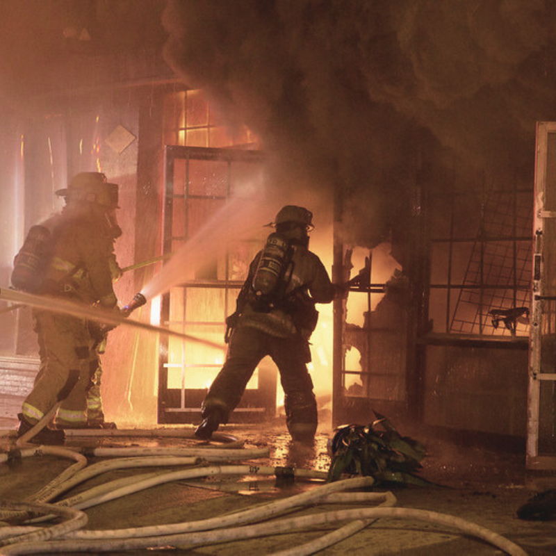 Firefighters battling a blaze in a smoky environment.