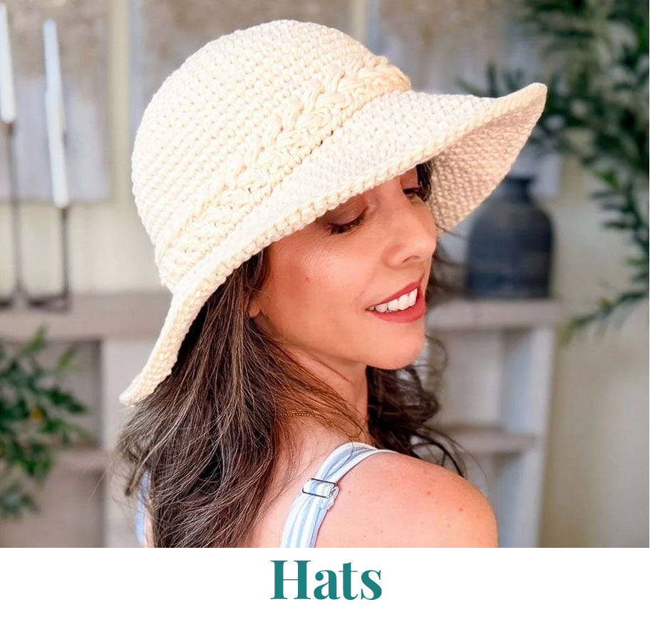A woman wearing a wide-brimmed hat, smiling softly.