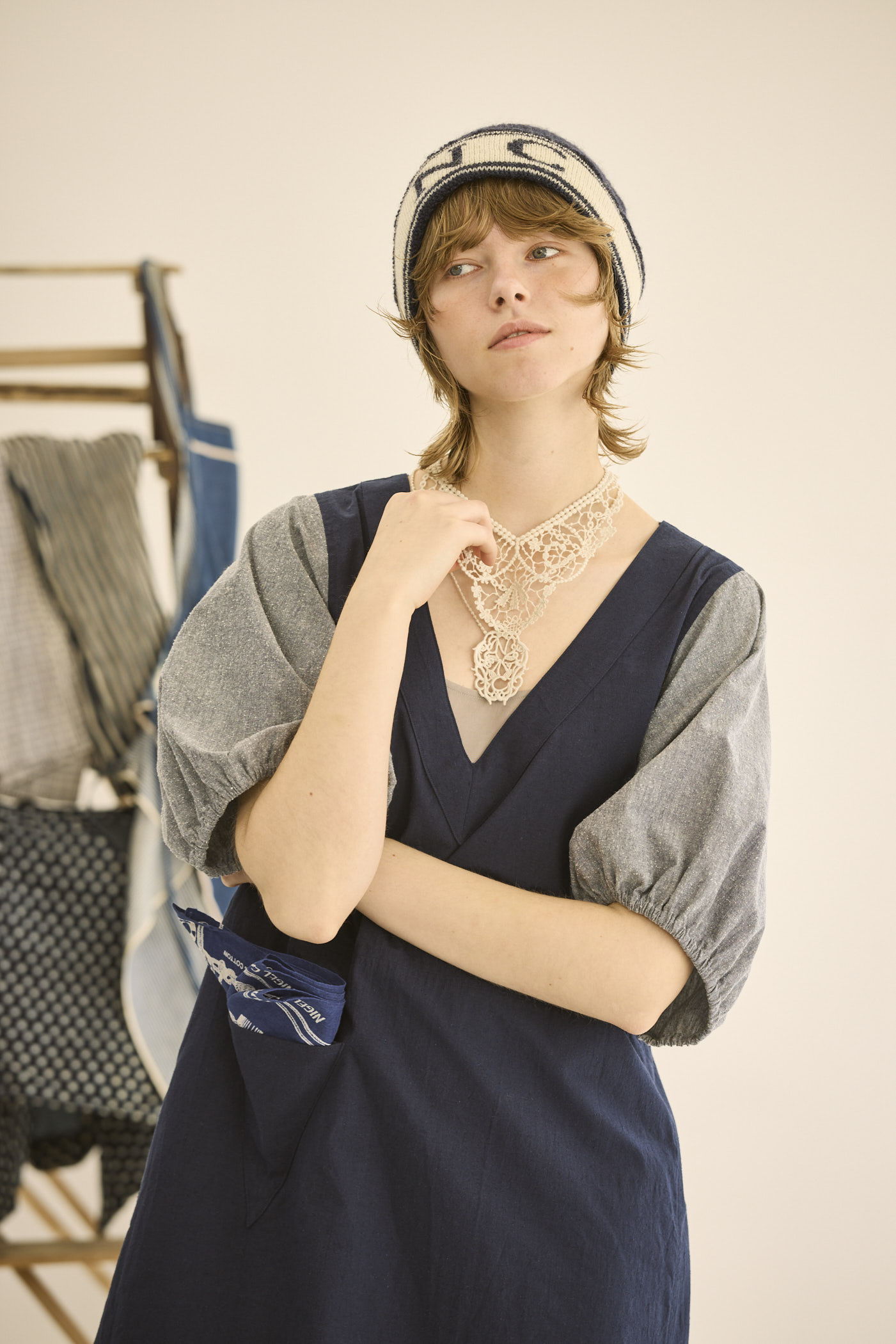 A person in a stylish outfit with a hat and jewelry posing indoors.