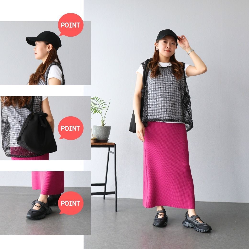 Woman in a pink skirt and black top, wearing a cap and posing.