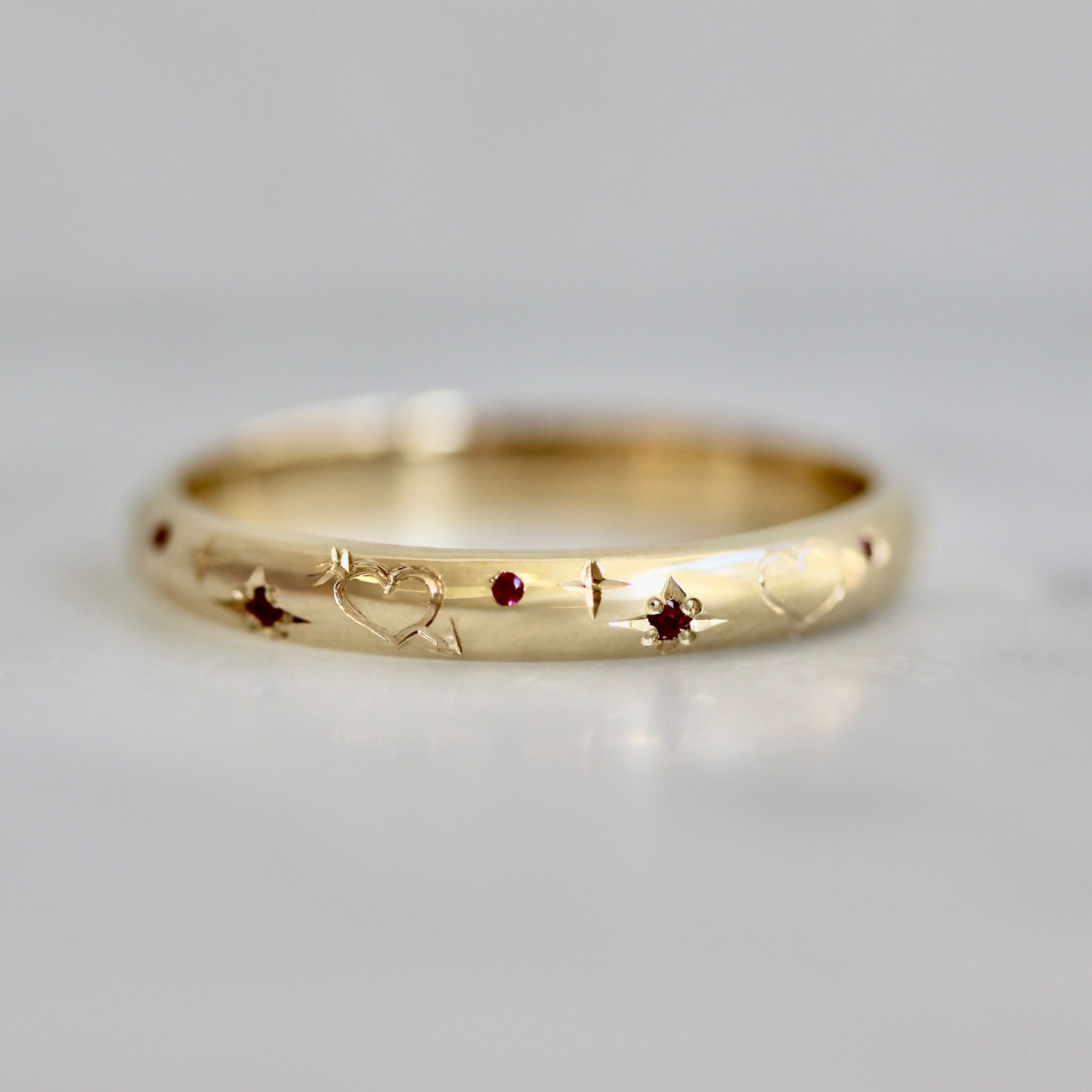 Hand-engraved wedding band with hearts, stars, and rubies