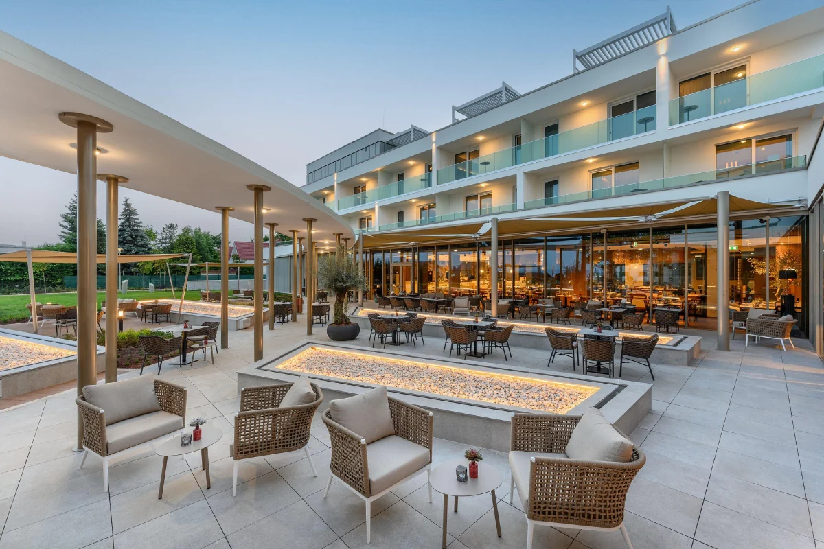 Luxury hotel courtyard with commercial outdoor furniture, dining tables, lounge chairs, and spacious circulation areas 