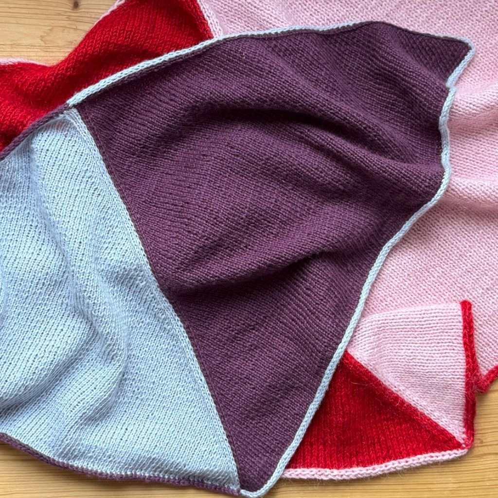 Gestrickte Dreieckstücher die übereinander drapiert sind.