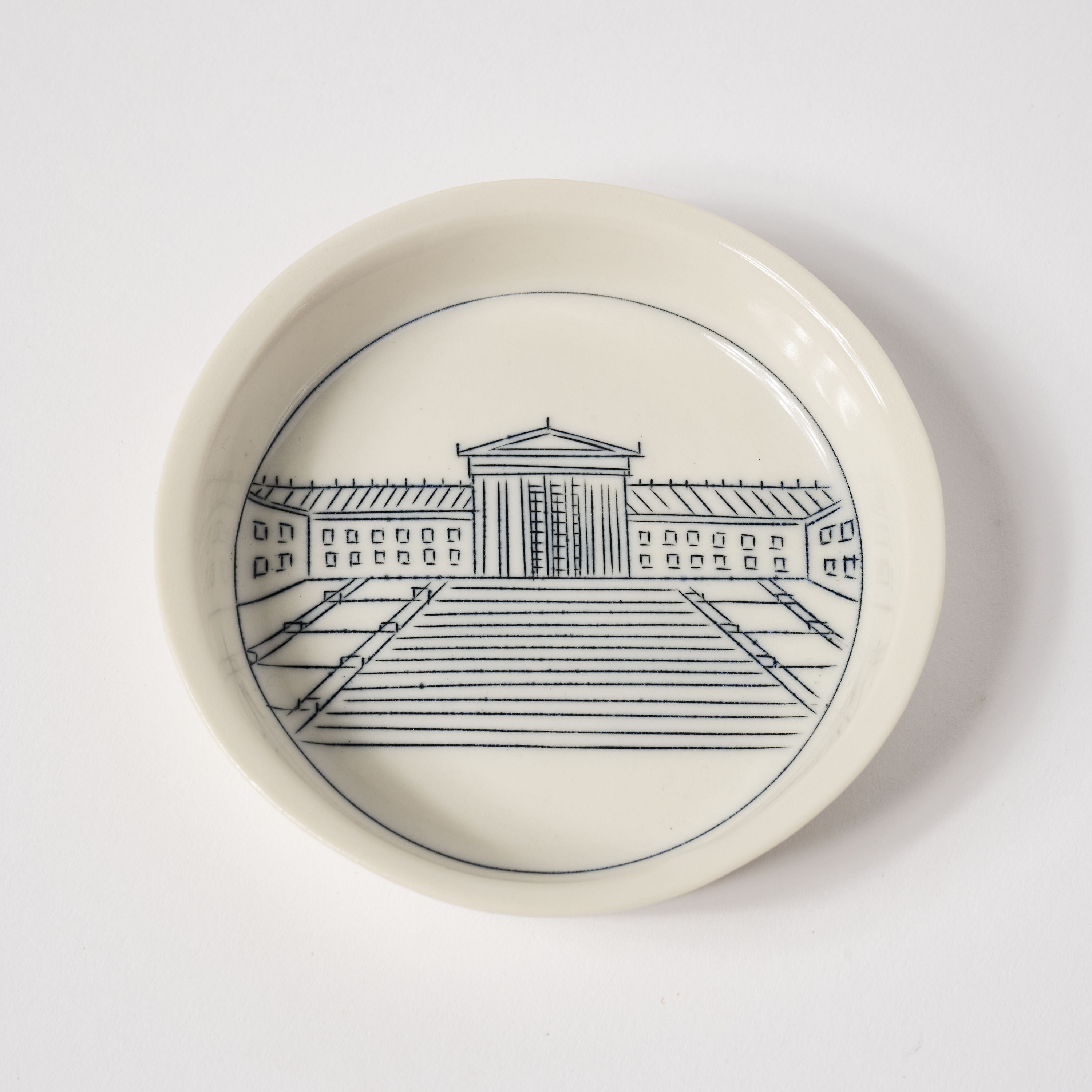 A round plate featuring a sketch of a building and steps.
