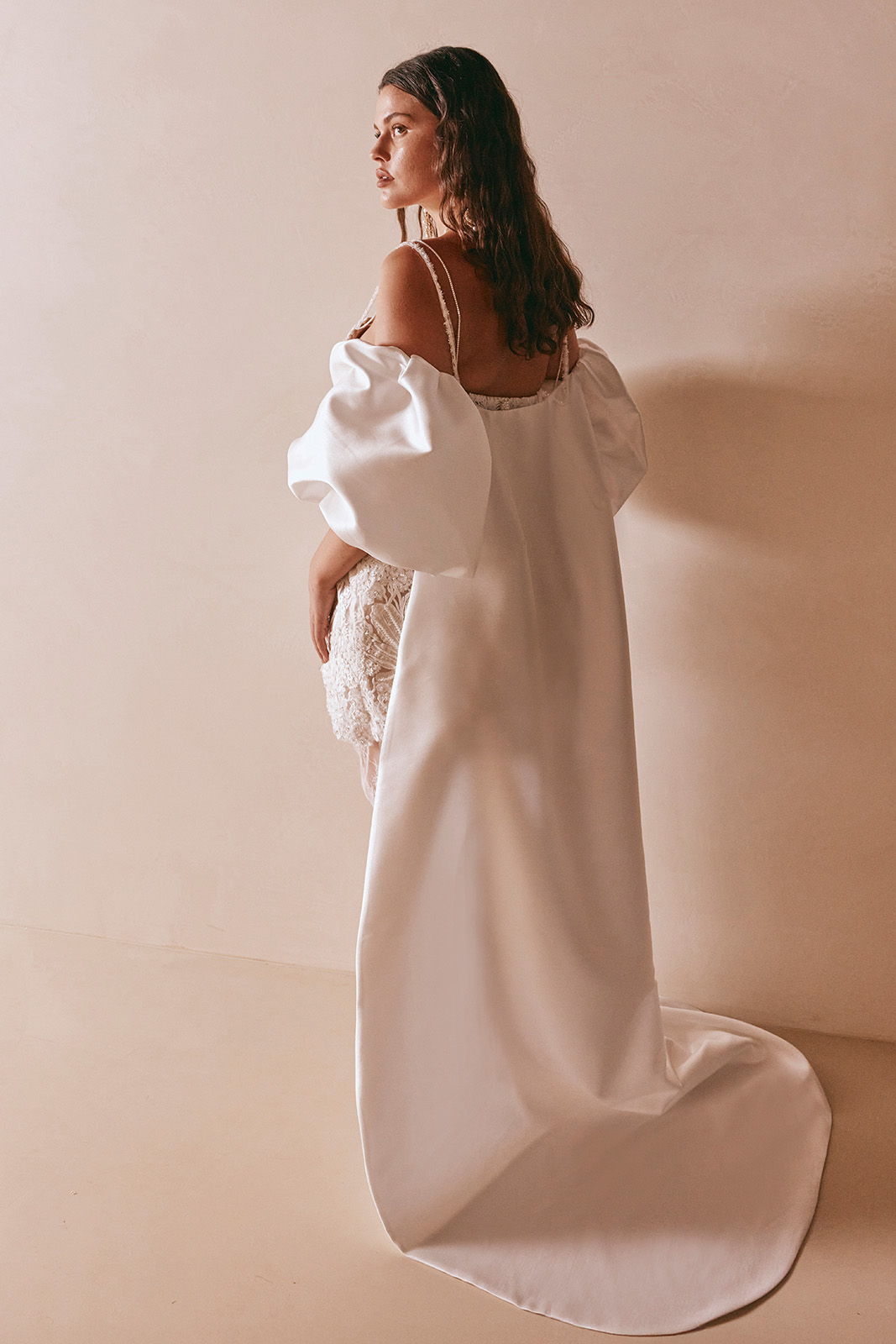 A woman in a white dress poses against a neutral background.