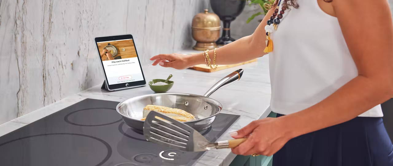 Woman cooking with Hestan Cue on induction cooktop