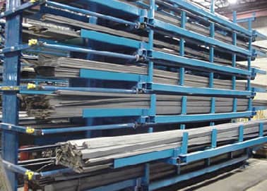 Metal rods stored on blue industrial racks in a warehouse.