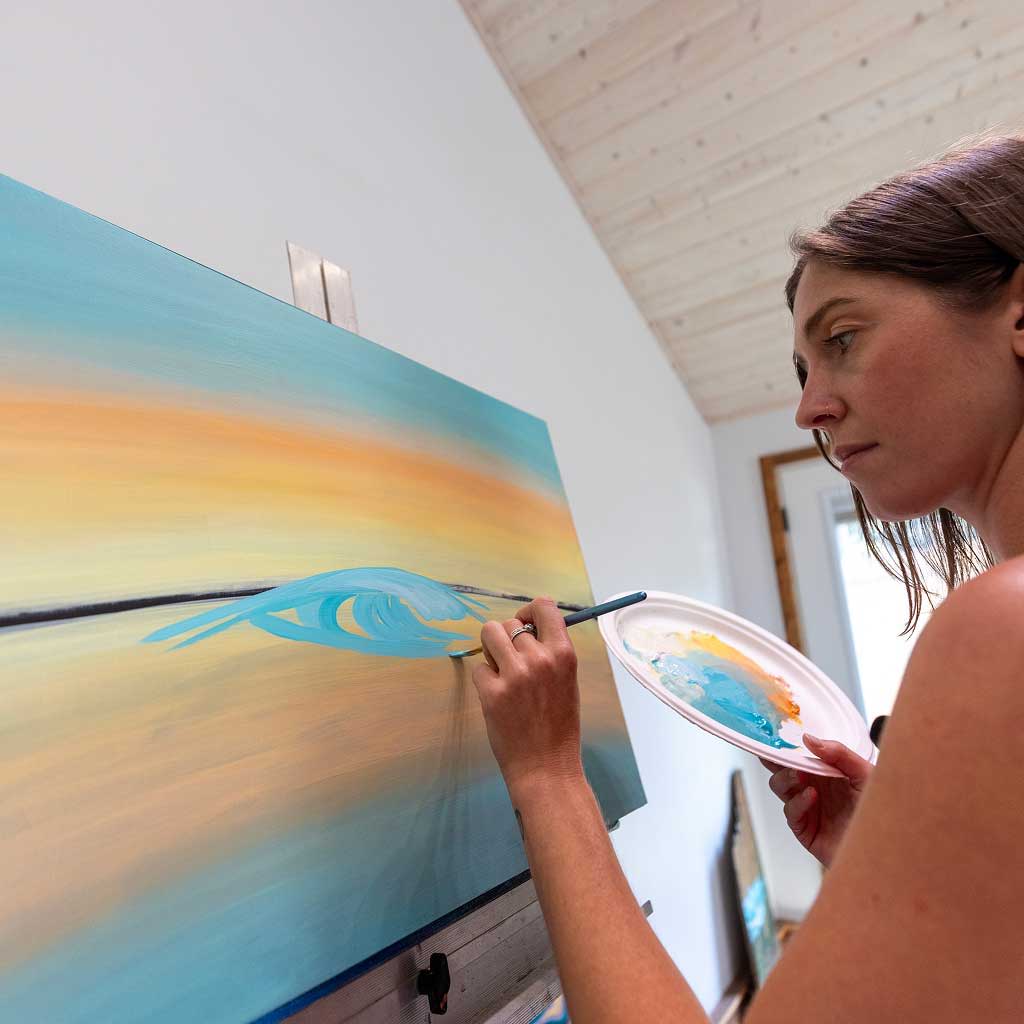 Gianna Andrews painting a colorful abstract artwork on a canvas.