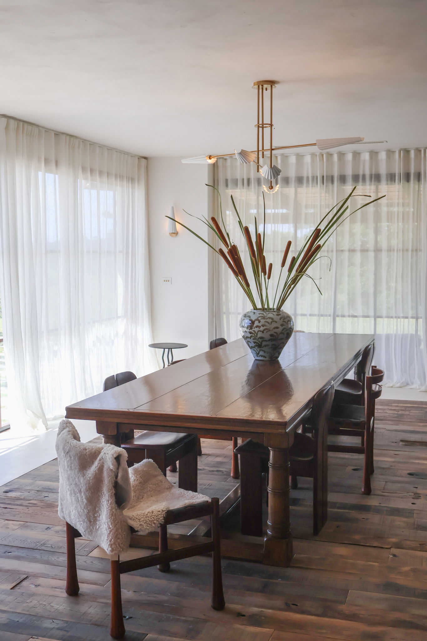 A dining room with a large table and a vase of flowers.