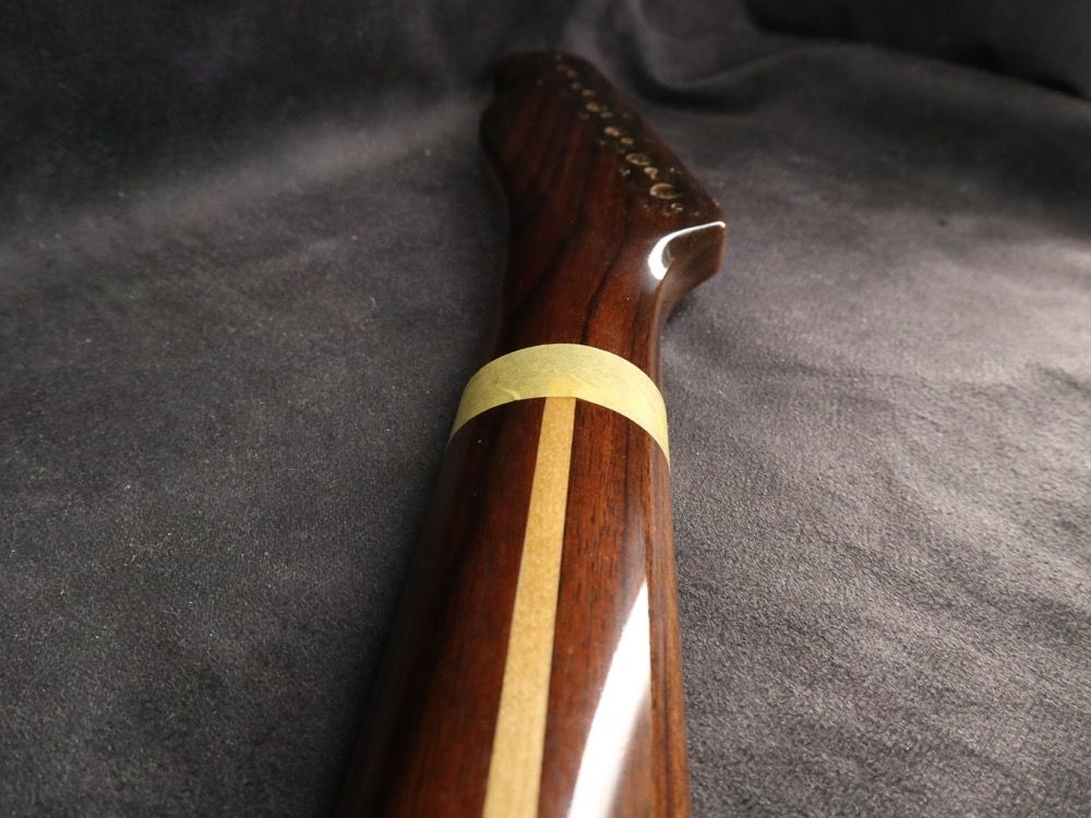Close-up of a wooden guitar neck with a decorative inlay.
