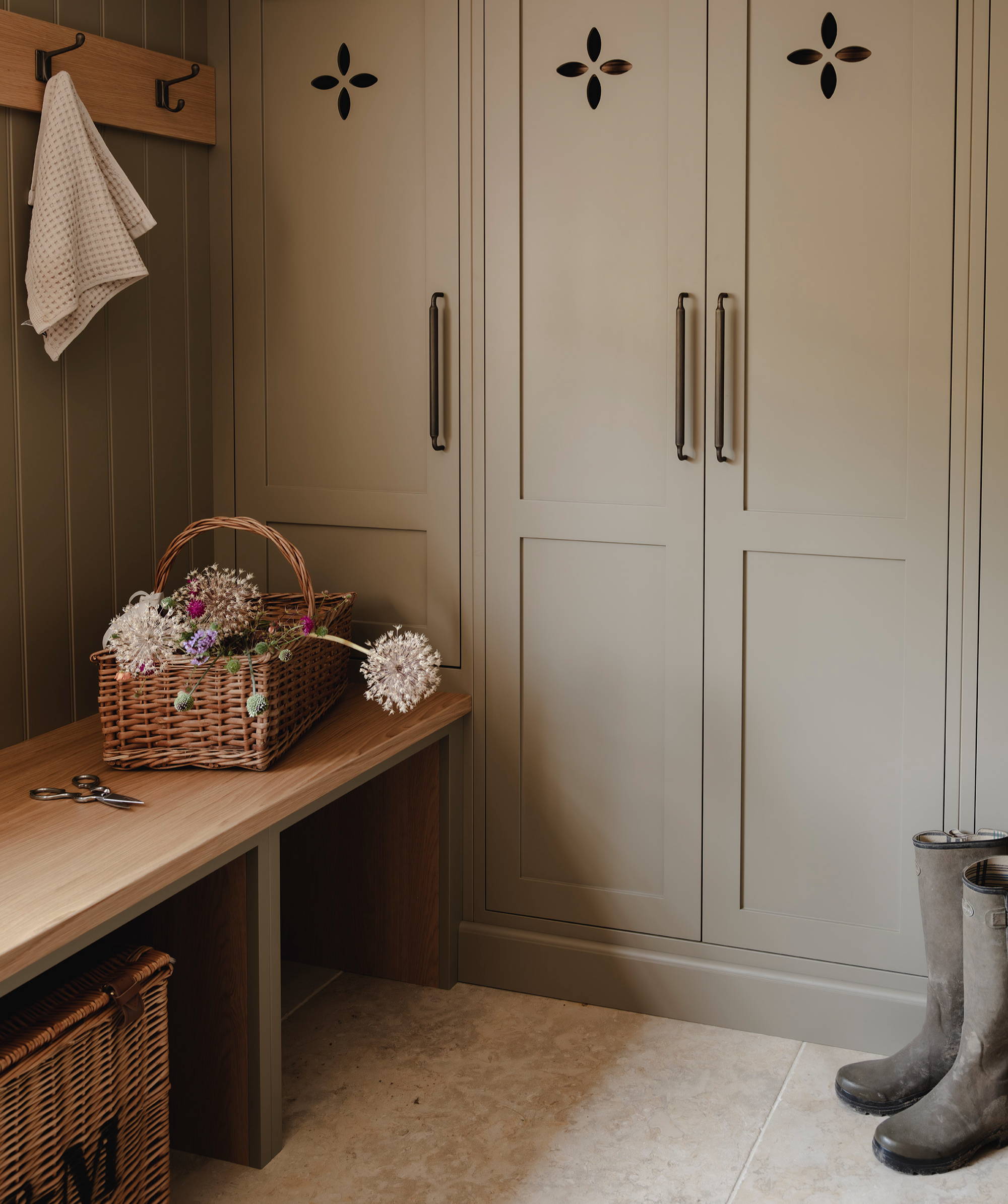 Earthy taupe cabinetry with brass handles and tiled floor in traditional mudroom