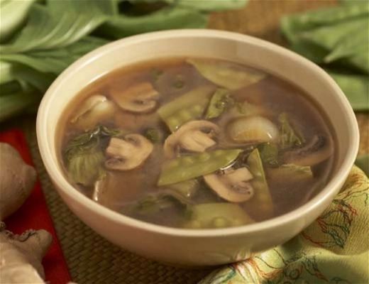 Bowl of vegetable soup with mushrooms and leafy greens.