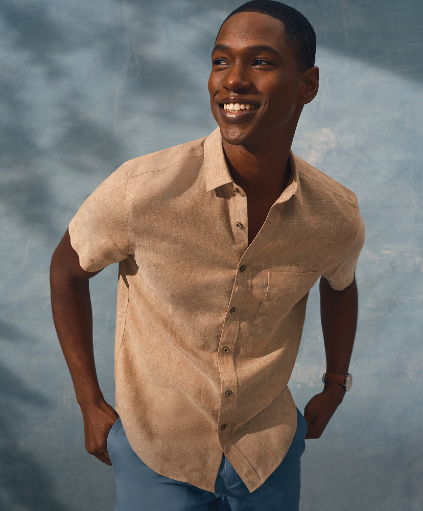 Smiling man in a light shirt against a soft blue background.
