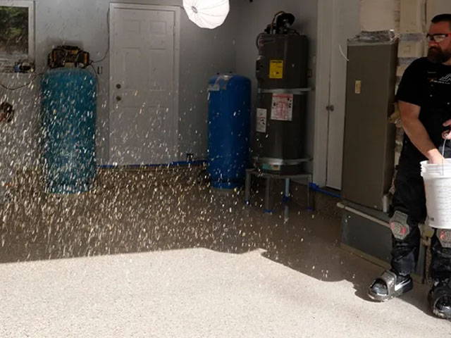 Flakes being dispersed onto the floor, allowing for a 24-hour curing period in a room above 65 degrees Fahrenheit.