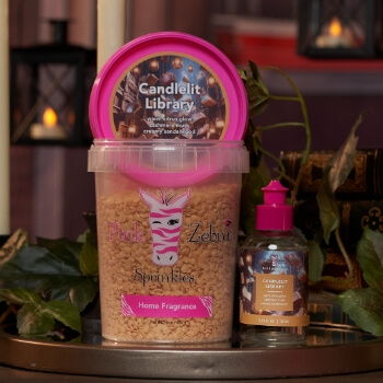 Container of scented wax and a small fragrance bottle on a table.