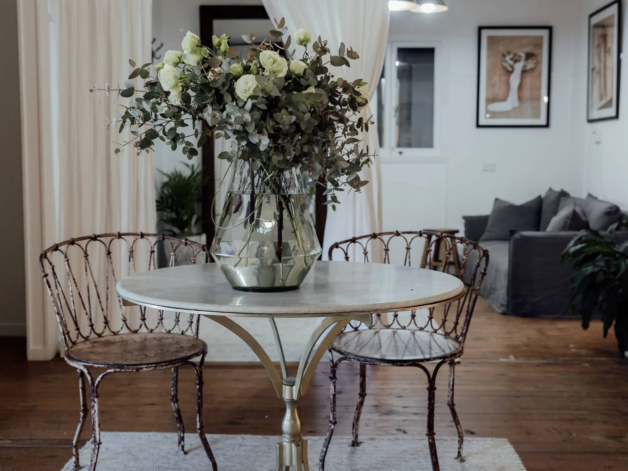 Deux chaises en cuivre à une table ronde avec un grand arrangement floral