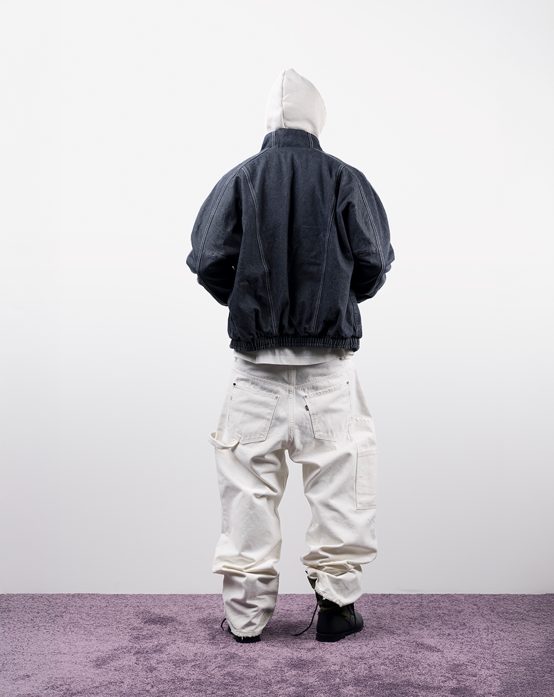 Person wearing a dark jacket and white pants, viewed from behind.