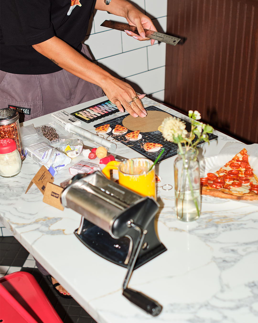 A person preparing food on a marble table with various ingredients and tools.