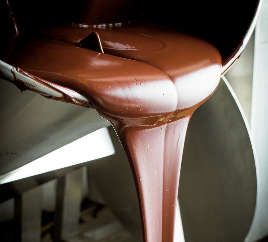 Pouring rich, melted chocolate from a machine.