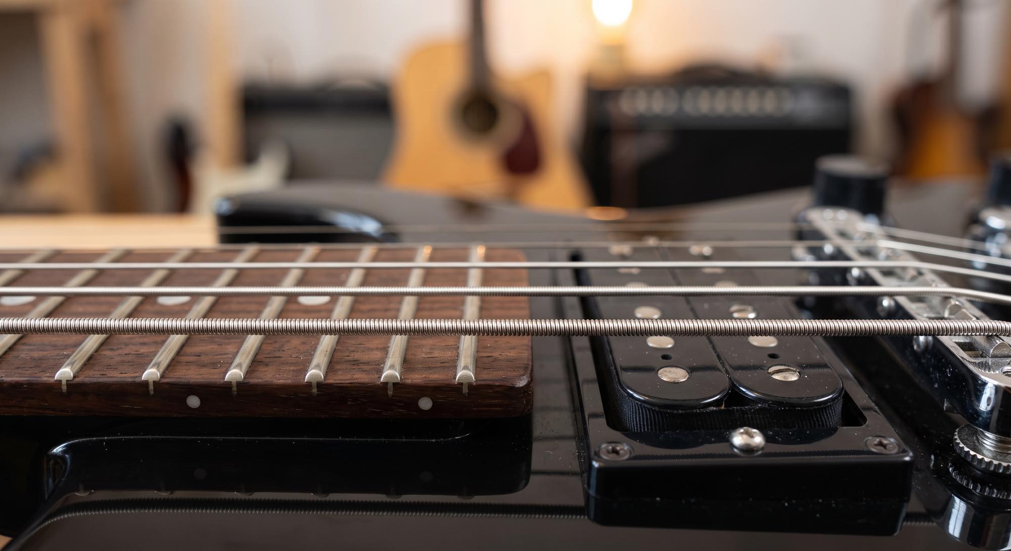 Nahaufnahme des Griffbretts und der Saiten einer schwarzen E-Gitarre.