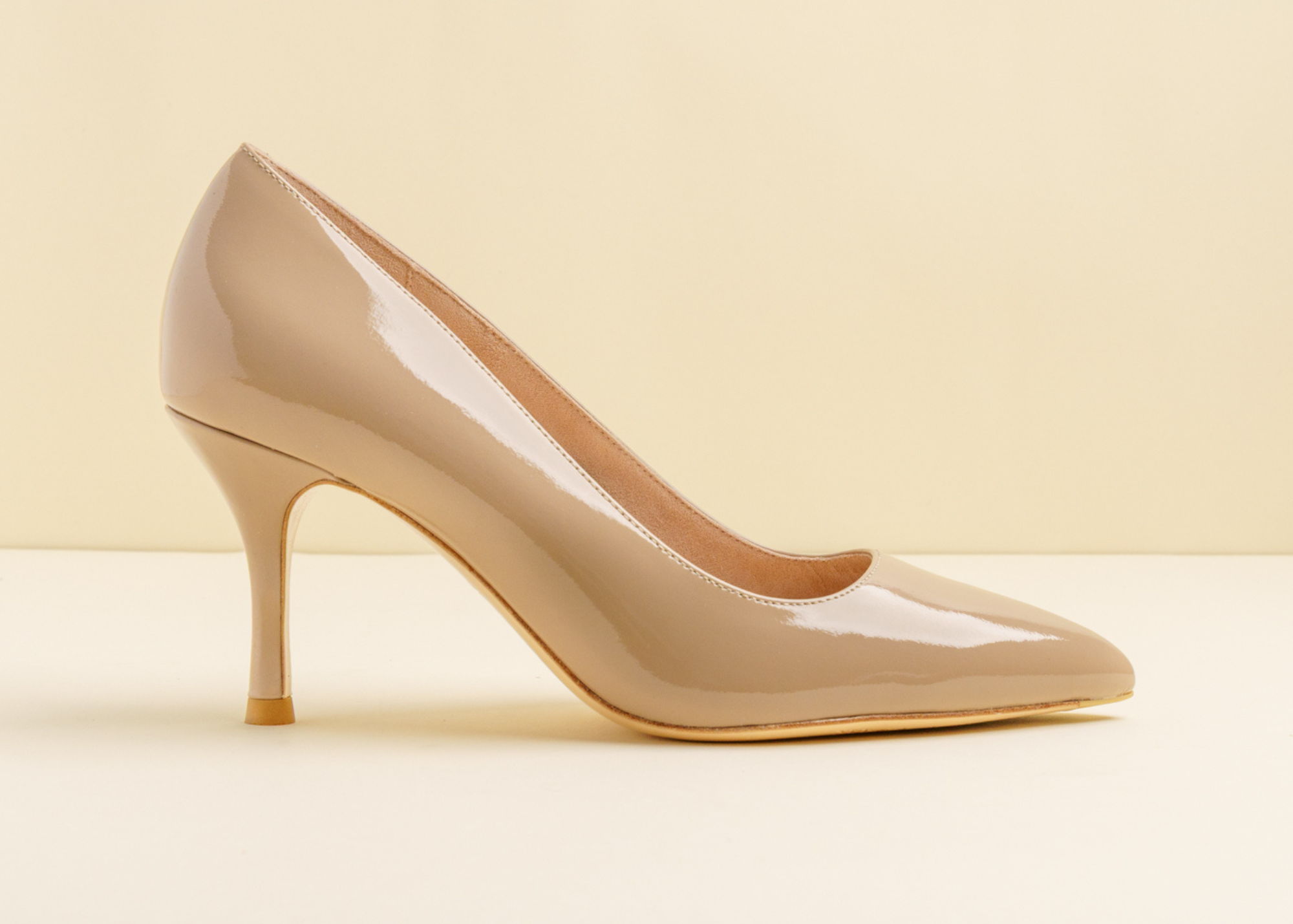 A beige high-heeled shoe on a neutral background.