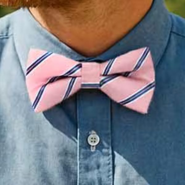 Closeup of a man wearing a pink pencil striped bow tie with a chambray shirt