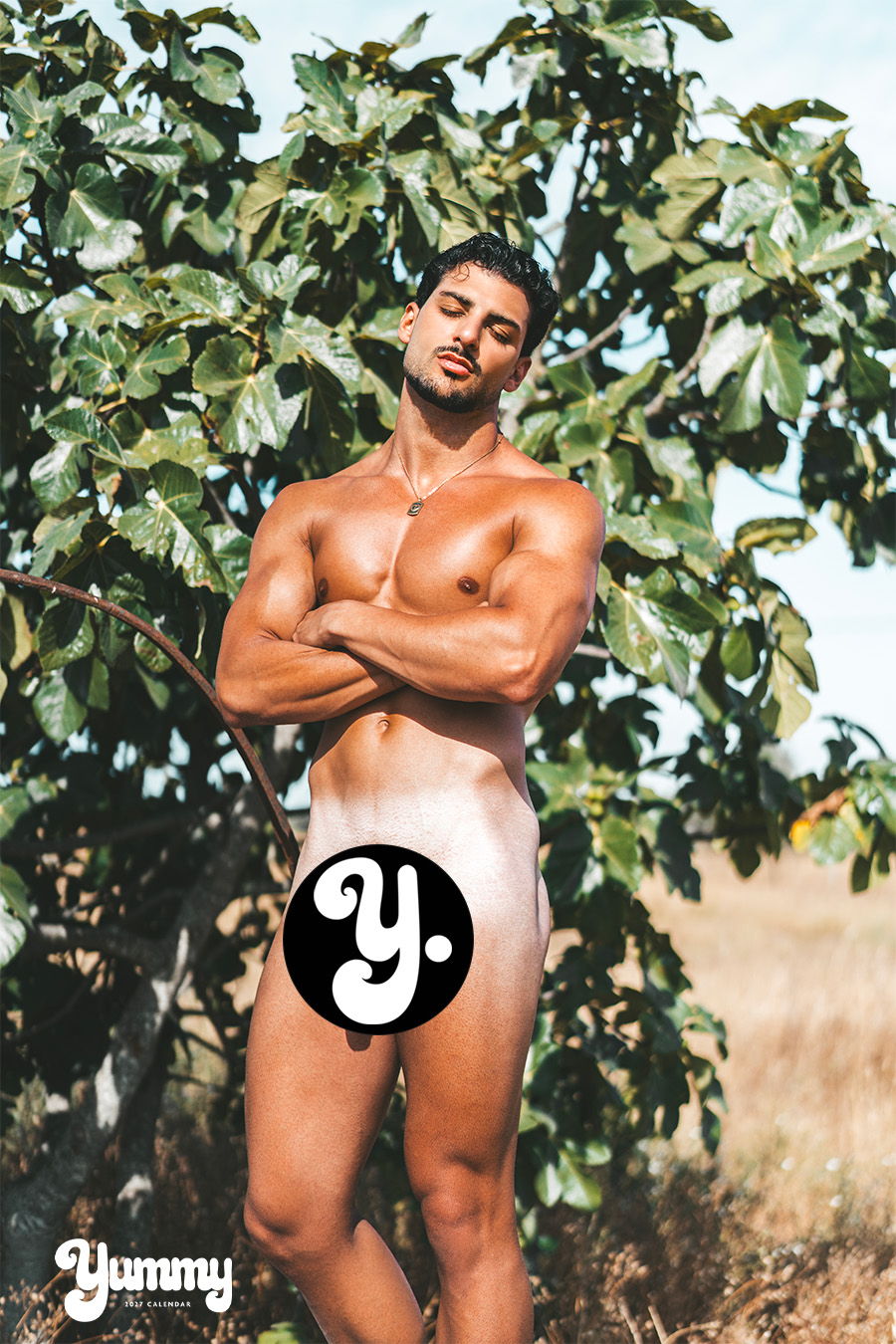 A muscular man poses confidently in front of a fig tree.