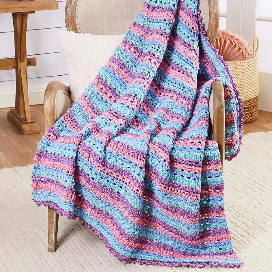 Colorful crochet blanket draped over a chair in a cozy setting.